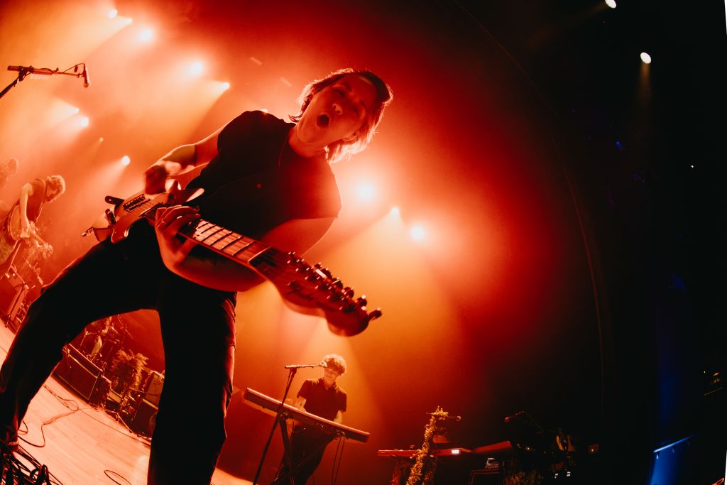 Ultimate Guide to Atlanta's Indie Music Scene 4 A musician passionately plays an electric guitar on stage, illuminated by warm, vibrant stage lights, with a bandmate singing into a microphone nearby in Atlanta, Georgia.