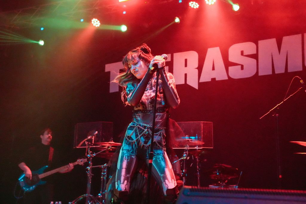 Ultimate Guide to Atlanta's Indie Music Scene 7 A performer in a metallic, chainmail-like outfit sings passionately into a microphone on stage, illuminated by vibrant red and green stage lights in Atlanta, Georgia.