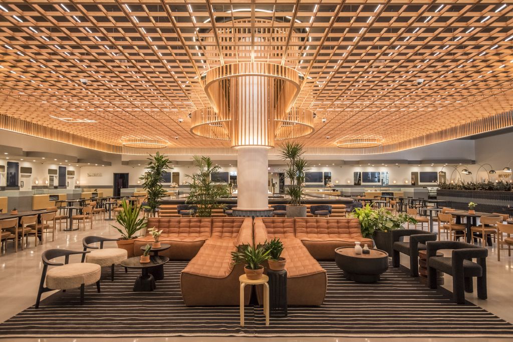 A spacious, modern lobby with a striking wooden ceiling, comfortable seating areas, and lush greenery in Atlanta, Georgia.