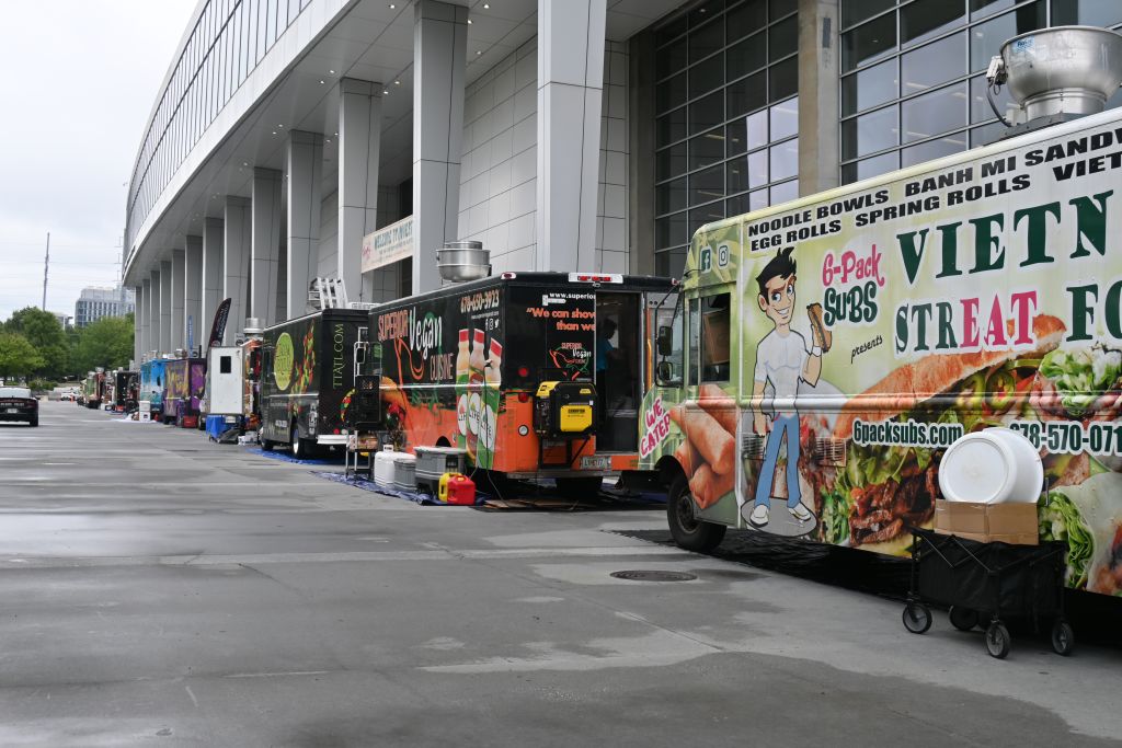 A row of colorful food trucks lined up outside a modern building, offering a variety of international cuisines in Atlanta, Georgia.