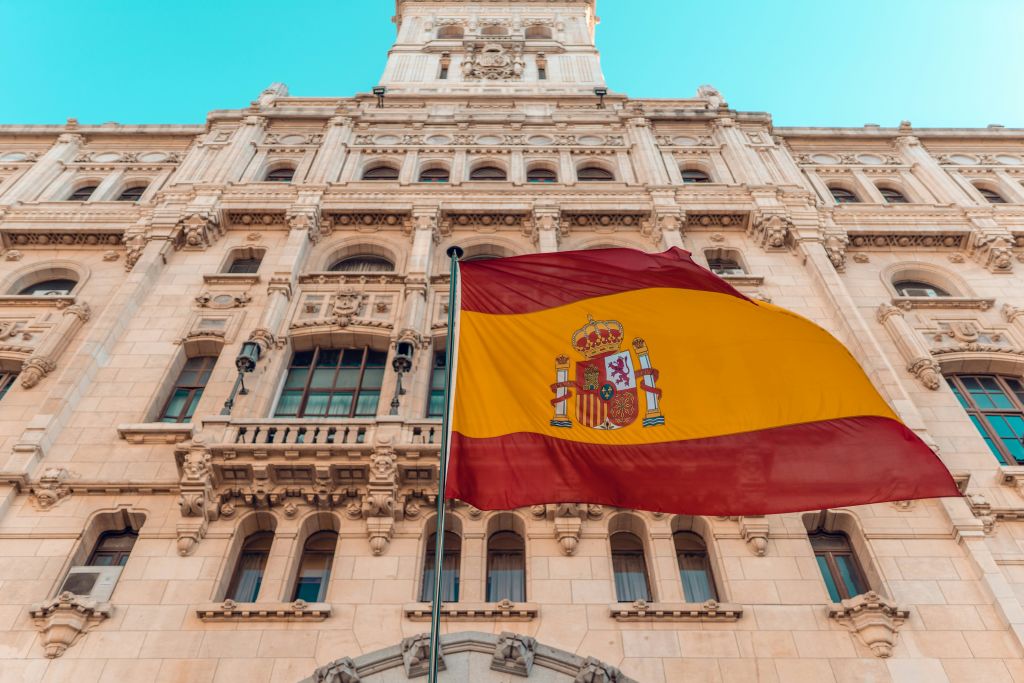 The Spanish flag waves proudly in front of a grand, historic building with intricate architectural details in Atlanta, Georgia.
