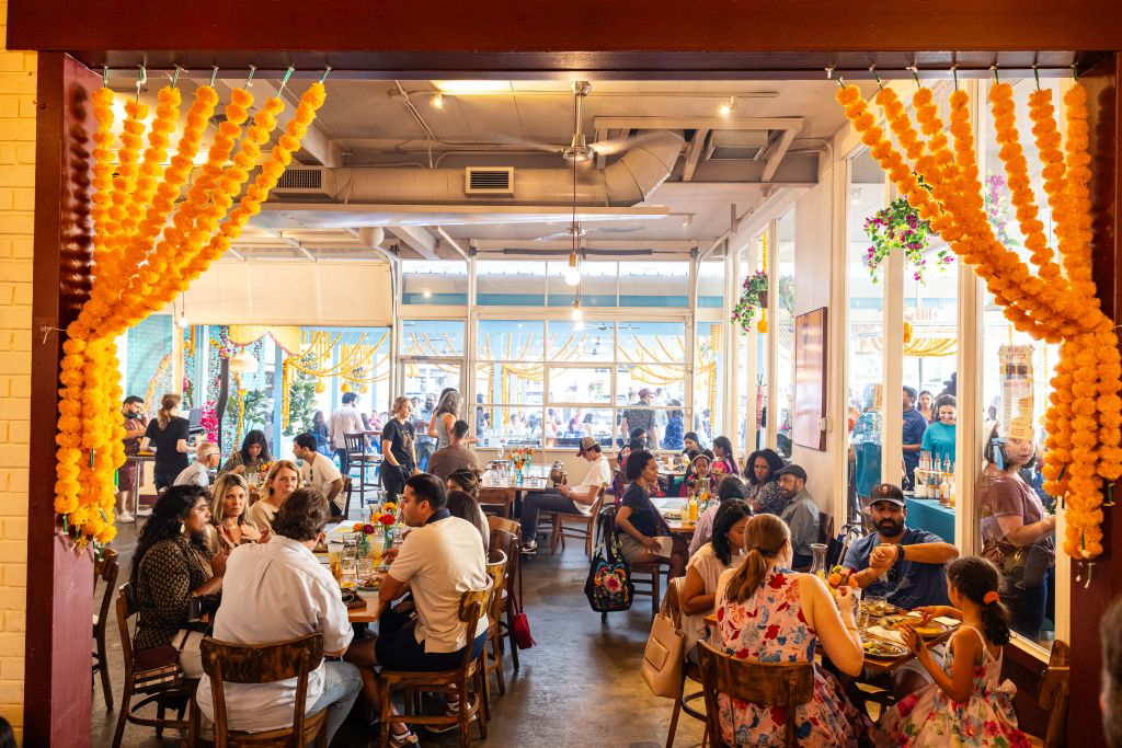 A vibrant restaurant filled with people enjoying meals, adorned with colorful flower garlands and festive decorations in Atlanta, Georgia.