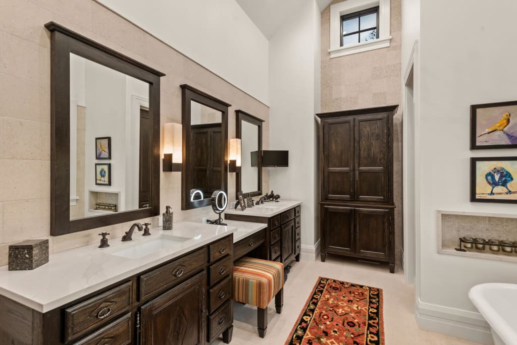 A luxurious bathroom with dark wood vanities, white marble countertops, and colorful artwork in Atlanta, Georgia.