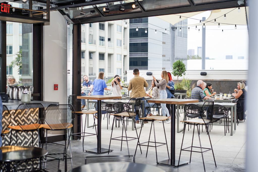 Outdoor rooftop bar with people socializing at tables and bar stools in Atlanta, Georgia.