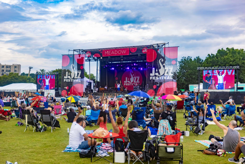 A lively outdoor jazz festival with a diverse crowd enjoying music on a grassy field in Atlanta, Georgia.