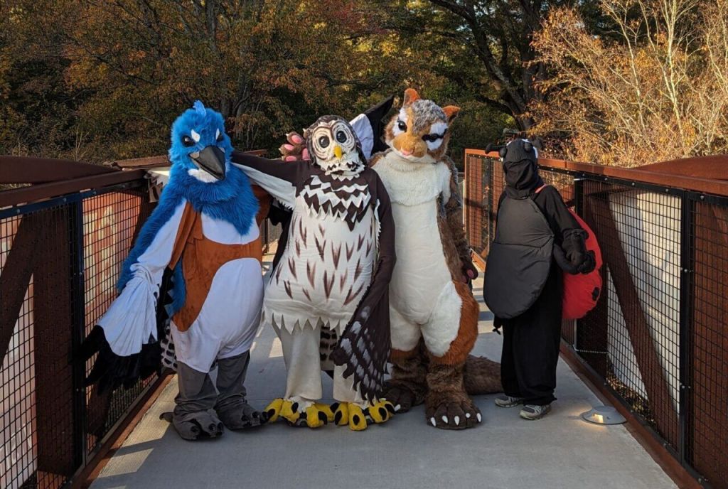 Four people in elaborate bird and animal costumes pose on a bridge in Atlanta, Georgia.