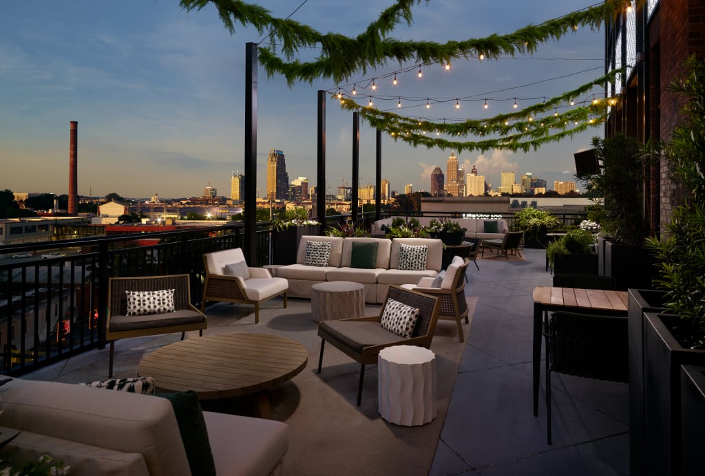 A rooftop patio at dusk with string lights, potted plants, and a view of the city skyline in Atlanta, Georgia.
