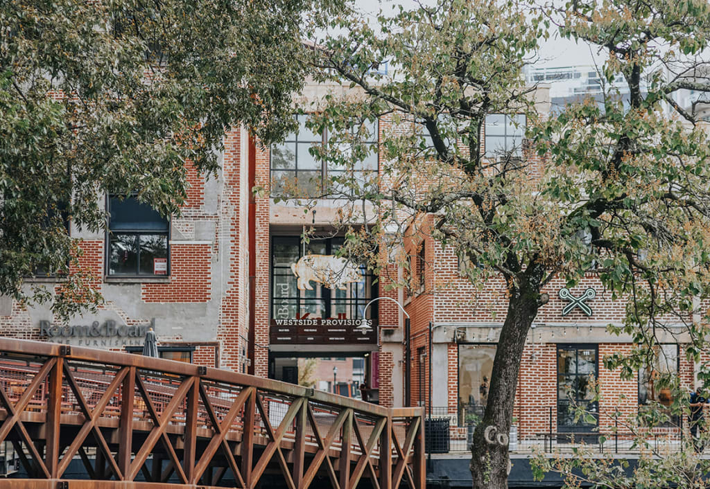 A rustic brick building with a tree and a metal bridge in front of it in Atlanta, Georgia.