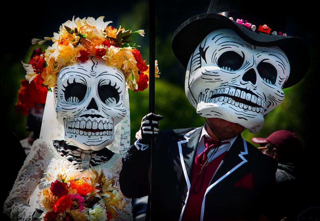 A couple dressed as elaborate sugar skulls for Dia de los Muertos, adorned with flowers in Atlanta, Georgia.