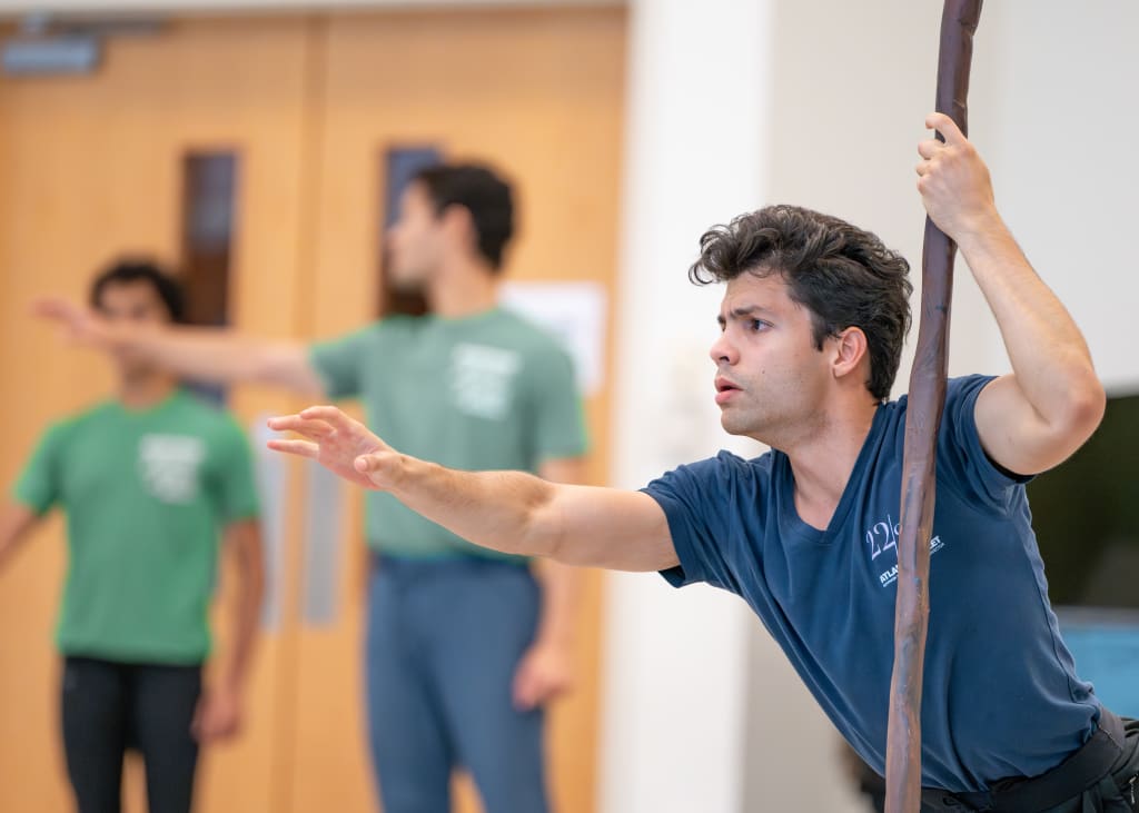 A man in a blue shirt holds a long stick, with two others in green shirts behind him in Atlanta, Georgia.