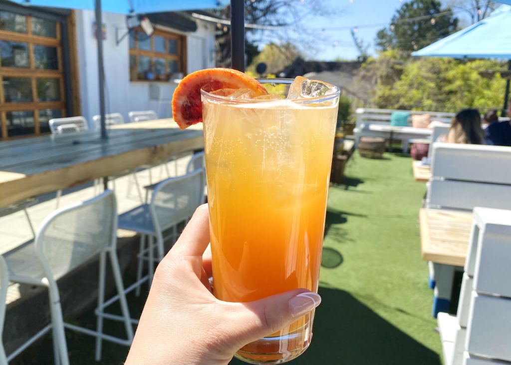 Hand holding orange drink.