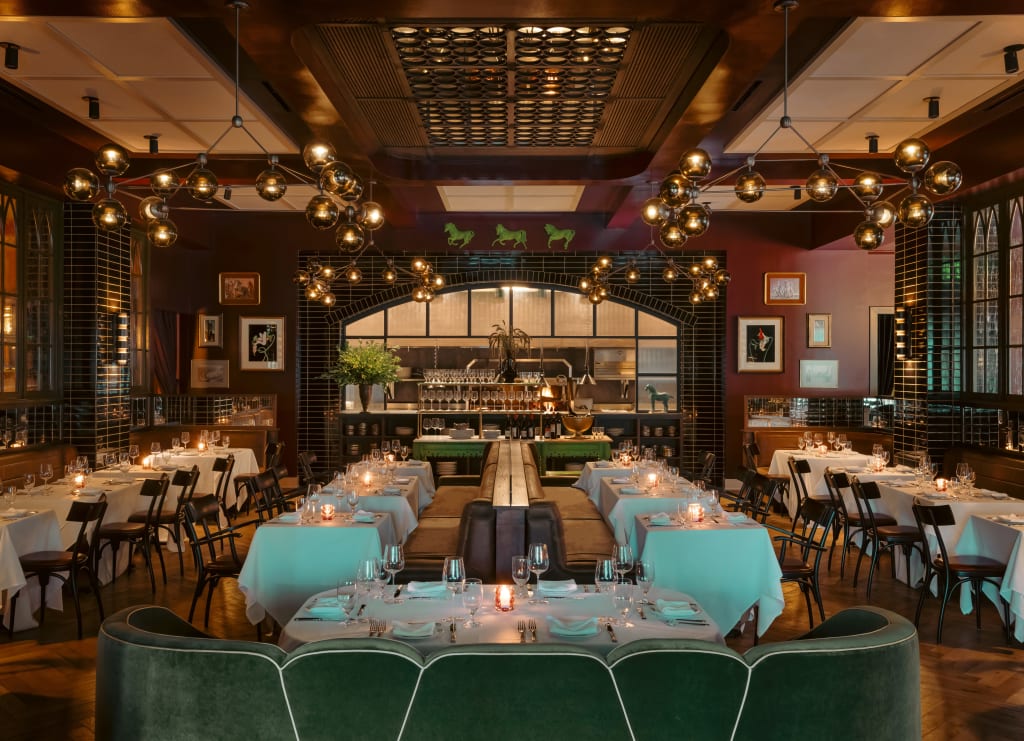 Elegant restaurant interior with green velvet seating, chandeliers, and white tablecloths in Atlanta, Georgia.