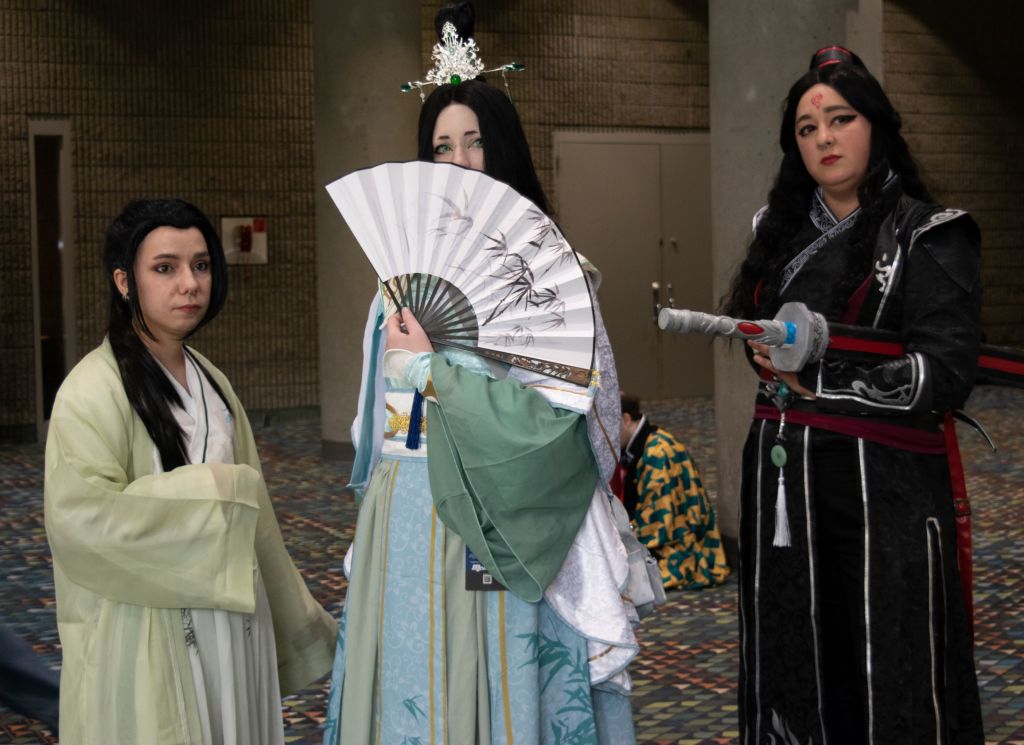 Three women in elaborate traditional Chinese costumes pose together at a convention in Atlanta, Georgia.