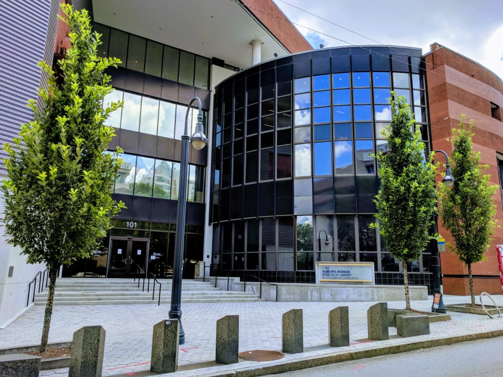 Auburn Avenue Research Library 1 Modern glass and concrete building with curved facade and trees in front in Atlanta, Georgia.