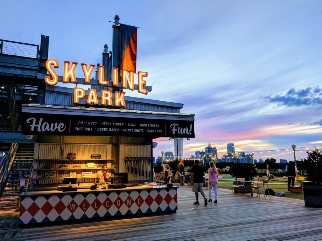 People enjoy evening activities at a rooftop amusement park with city skyline views in Atlanta, Georgia.