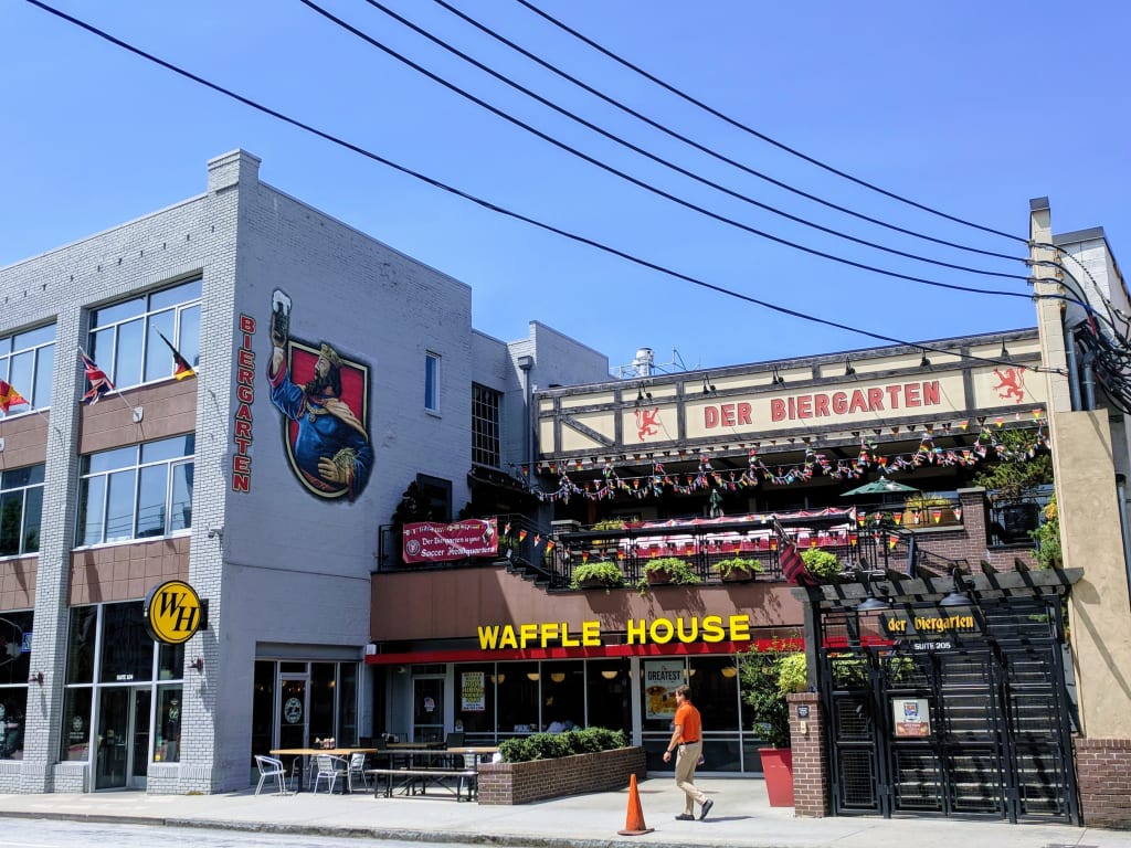 A man walks past a Waffle House and a German-themed restaurant with outdoor seating in Atlanta, Georgia.