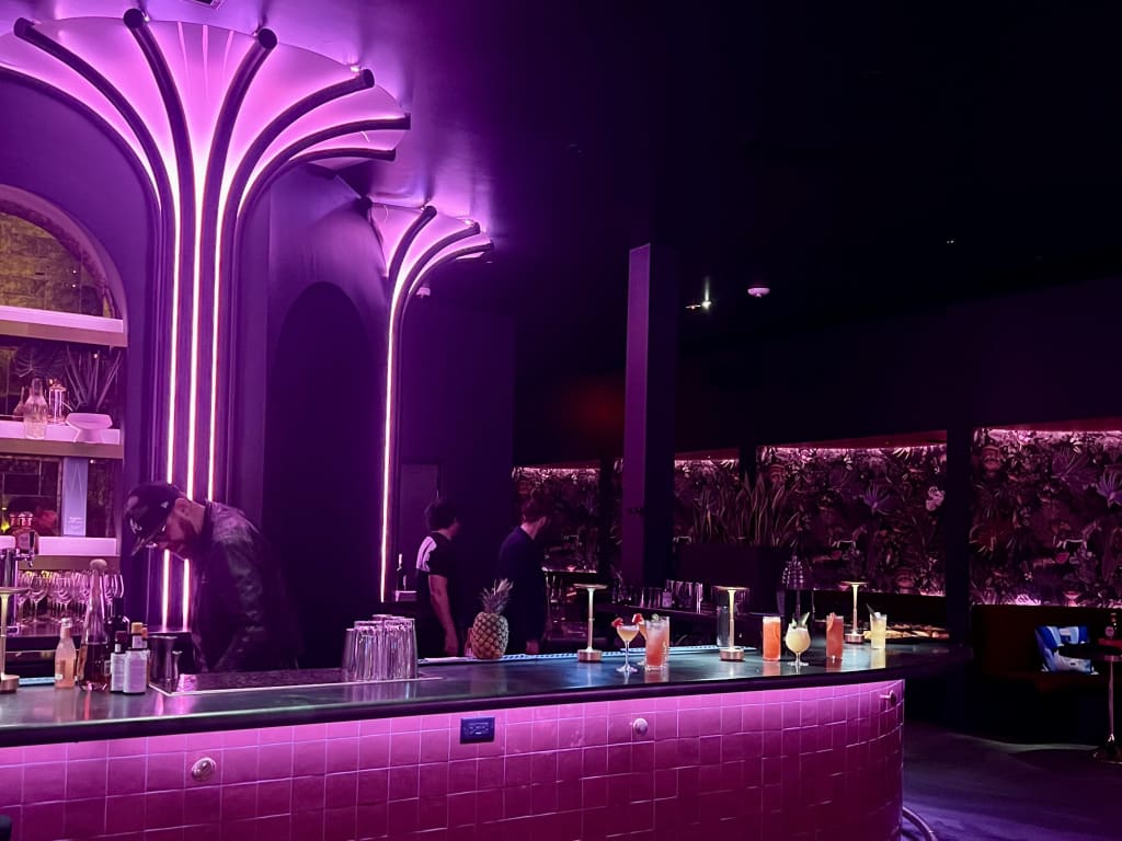 A dimly lit bar with neon lights and a variety of colorful cocktails on display in Atlanta, Georgia.