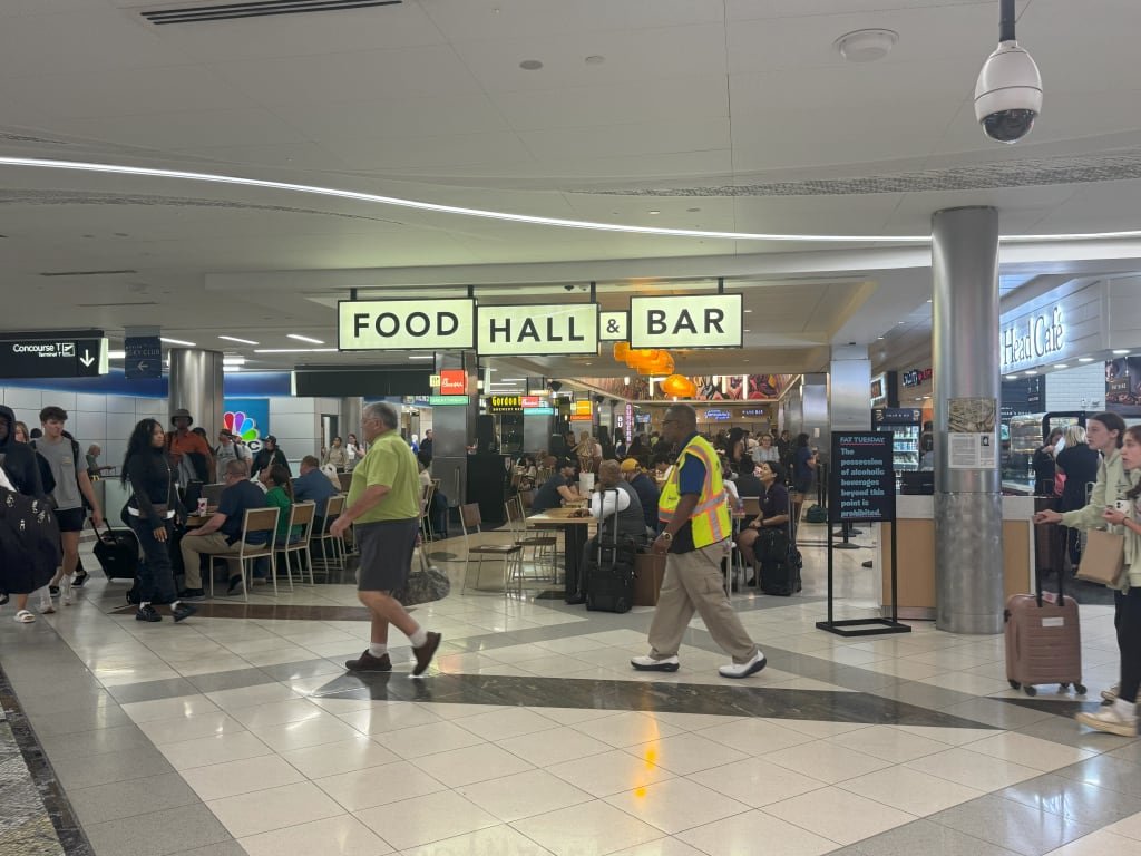 A bustling airport food court with diverse patrons, signs, and seating areas in Atlanta, Georgia.