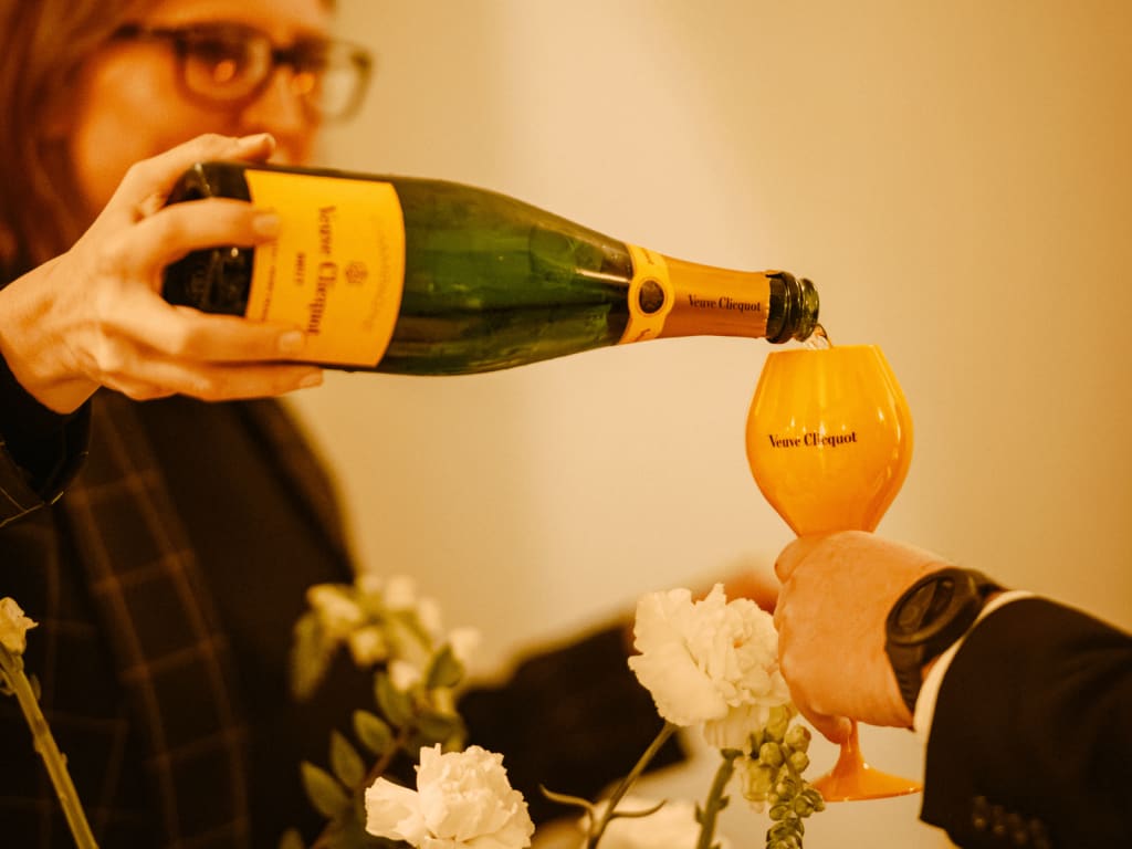 A woman pours champagne from a Veuve Clicquot bottle into a matching yellow flute in Atlanta, Georgia.