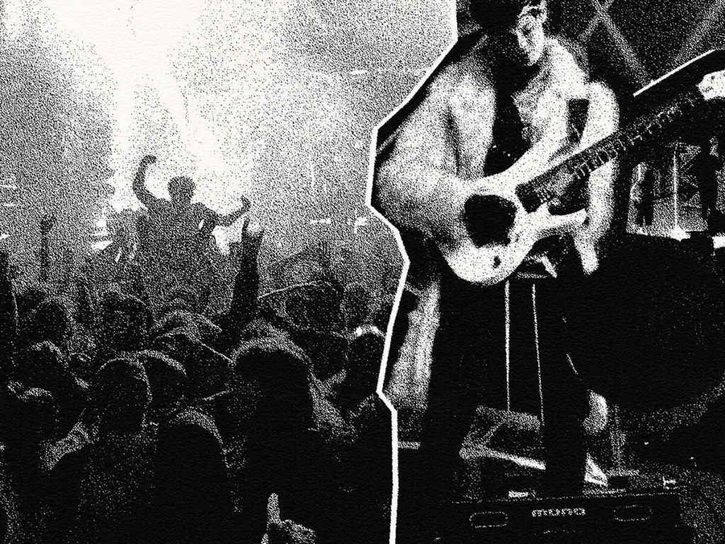 A musician performs on stage, playing an electric guitar amidst a lively crowd at a concert in Atlanta, Georgia.