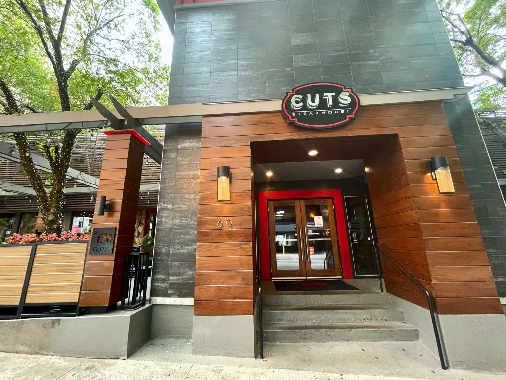 Modern steakhouse with wooden facade, red doors, and outdoor seating area in Atlanta, Georgia.