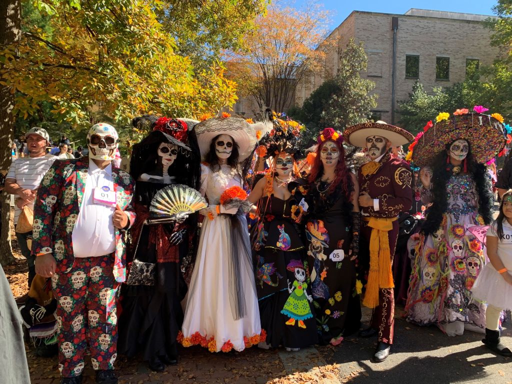 A group of people dressed in colorful, elaborate costumes for a Day of the Dead celebration in Atlanta, Georgia.