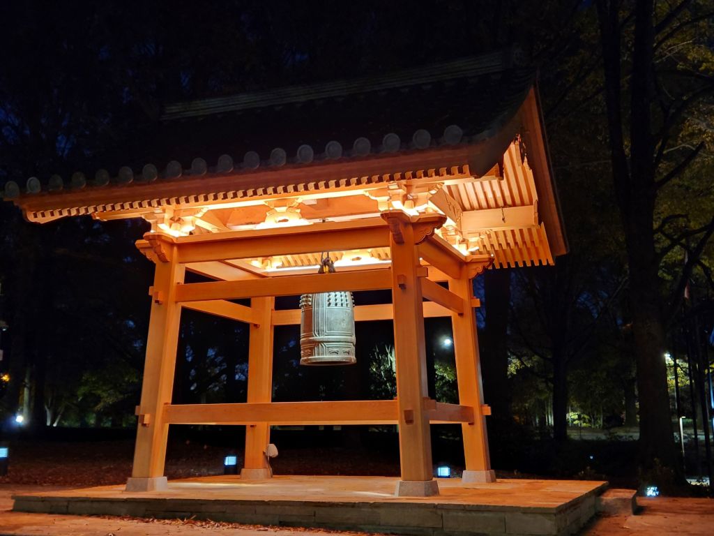 A traditional Japanese bell tower illuminated at night with intricate wooden architecture in Atlanta, Georgia.
