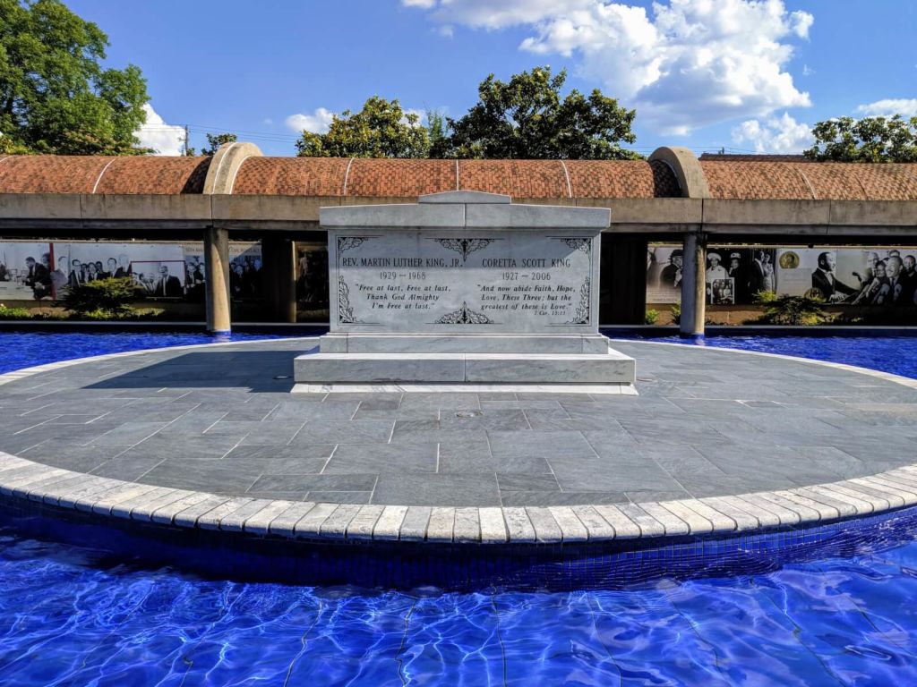 A circular pool with a blue center surrounds a white marble monument featuring inscriptions in Atlanta, Georgia.