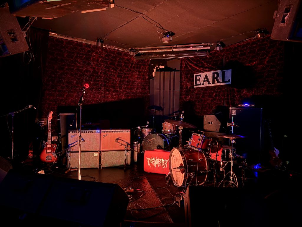 A dimly lit stage with musical instruments and amplifiers set up, ready for a performance in Atlanta, Georgia.