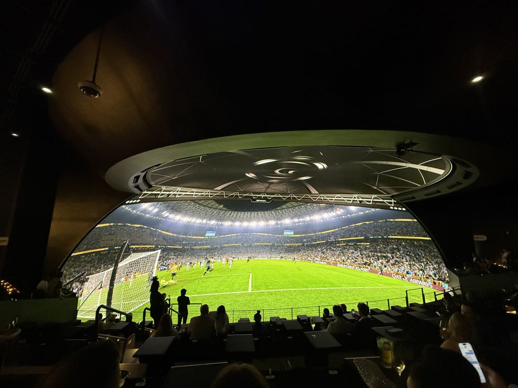 A panoramic view of a packed stadium with a vibrant green soccer field illuminated by bright lights, showcasing a thrilling match between two teams in Atlanta, Georgia.