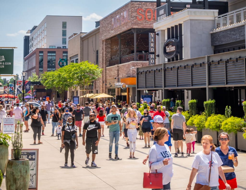 Crowded urban street scene with pedestrians, shops, and outdoor seating areas in Atlanta, Georgia.
