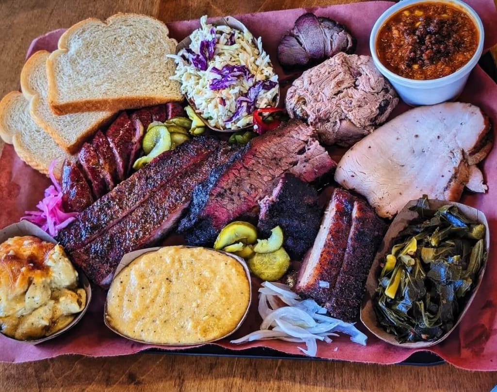 A large platter of barbecue meats, sides, and condiments, including ribs, brisket, pulled pork, and coleslaw in Atlanta, Georgia.