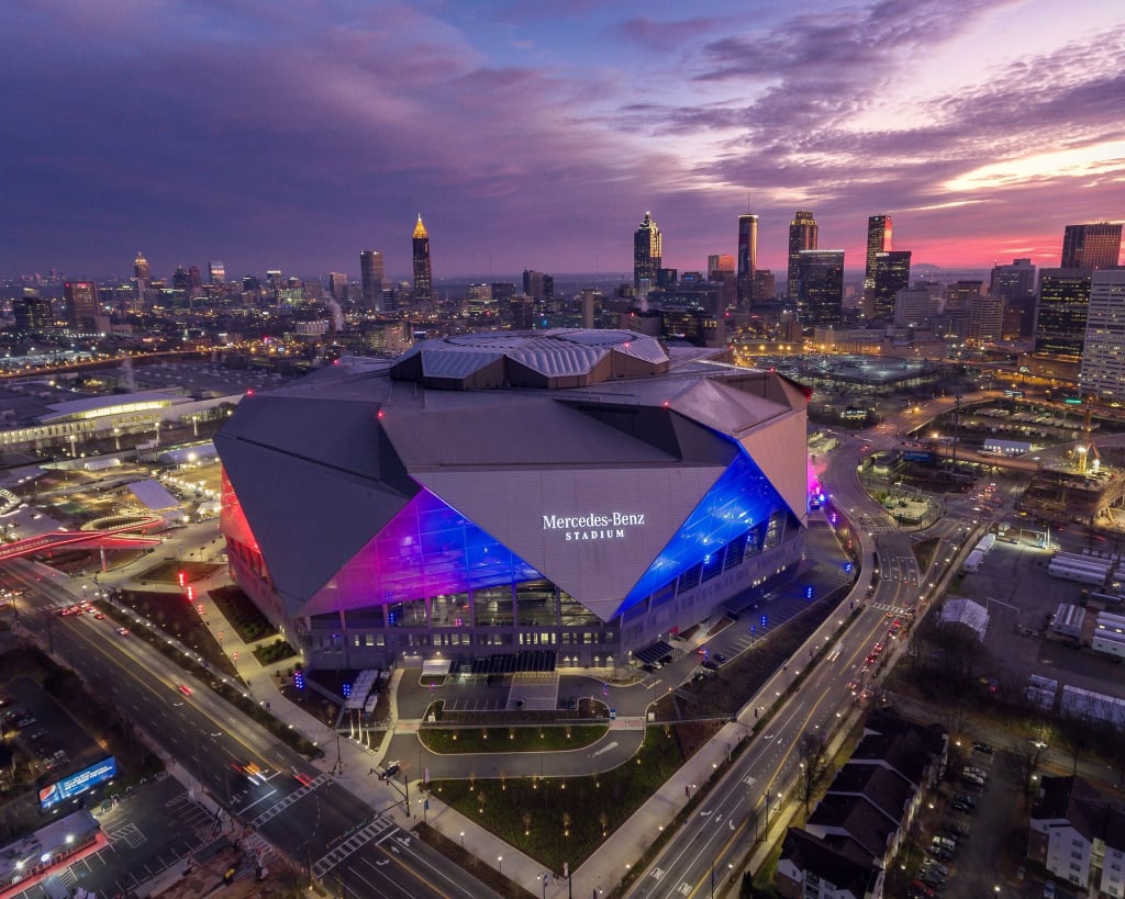 A futuristic stadium with a distinctive roof lights up the Atlanta skyline at dusk in Atlanta, Georgia.