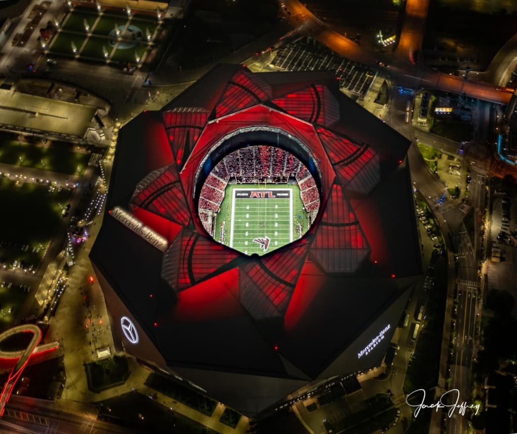 Aerial view of Mercedes-Benz Stadium, Atlanta, with red roof and lit football field in Atlanta, Georgia.