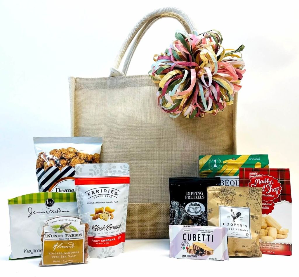 A gift basket filled with gourmet snacks and treats, including popcorn, nuts, cheese straws, and chocolate, presented in a stylish burlap tote bag with a colorful ribbon in Atlanta, Georgia.