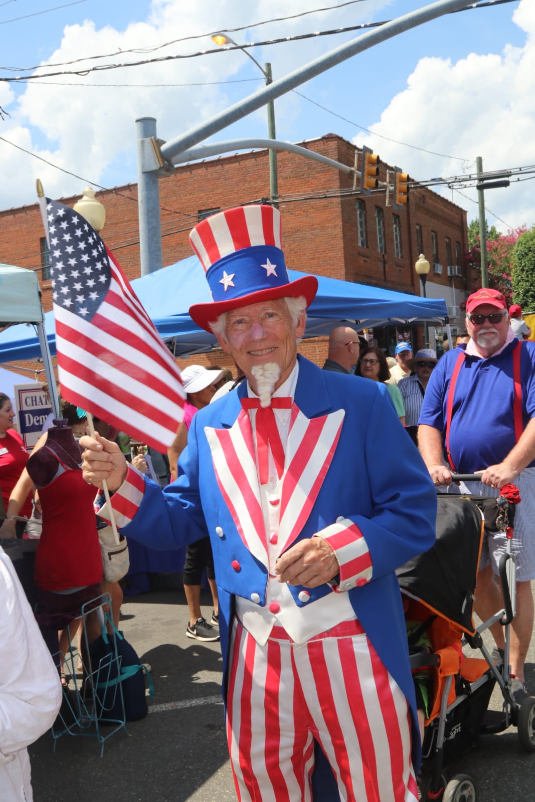 Independence Day Fireworks Light Metro Atlanta Skies 6 Man dressed as Uncle Sam waves American flag at outdoor event in Atlanta, Georgia.