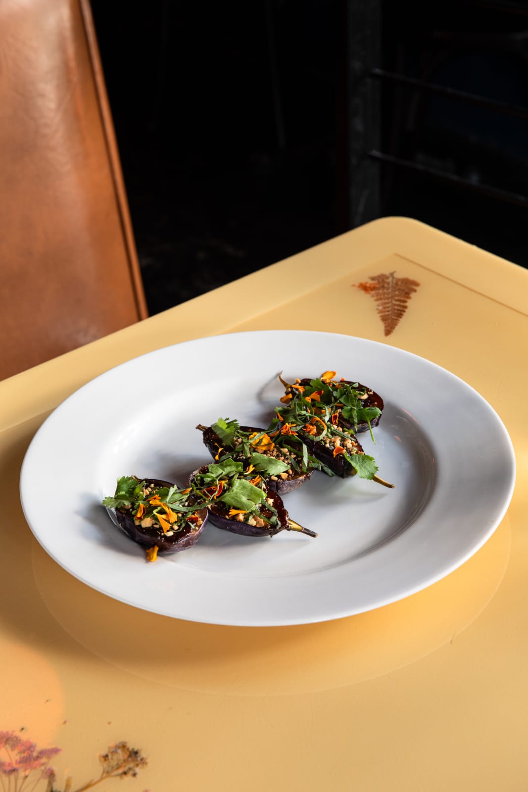 Four stuffed eggplants garnished with herbs and spices on a white plate in Atlanta, Georgia.