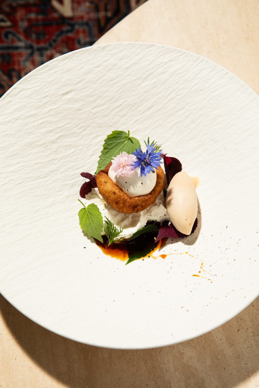 Artfully plated dessert with edible flowers, cream, and a crispy base on a white plate in Atlanta, Georgia.