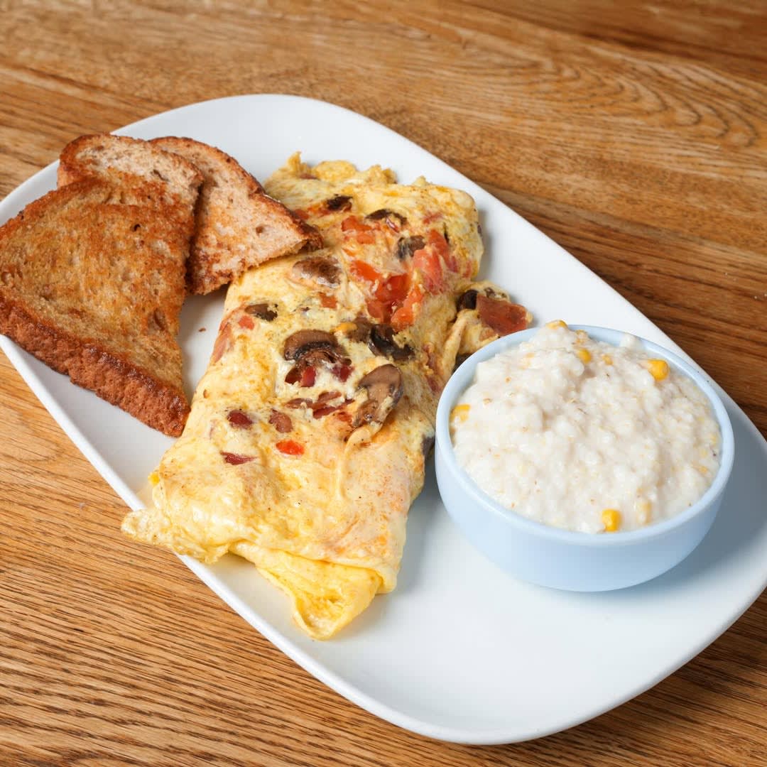 Inman Park 9 A plate with a vegetable and cheese omelet, two slices of whole grain toast, and a bowl of grits in Atlanta, Georgia.