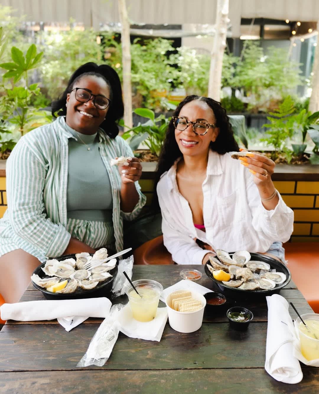 Two women enjoying a meal of oysters and drinks at an outdoor restaurant in Atlanta, Georgia.