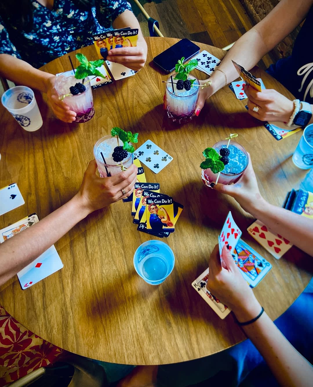 A group of women gather around a table, enjoying drinks and playing cards in Atlanta, Georgia.