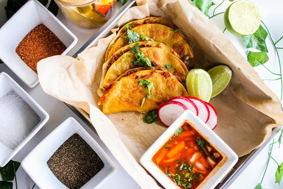 A tray of crispy tacos garnished with cilantro, radishes, and lime wedges in Atlanta, Georgia.