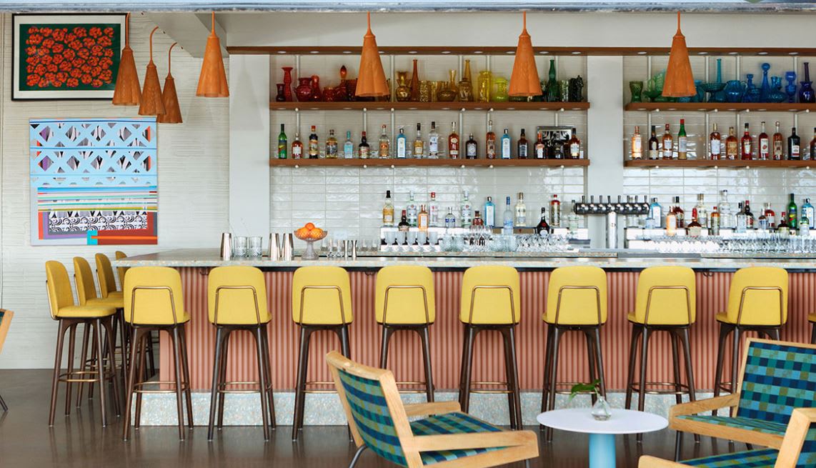 Development 23 A stylish bar with yellow stools, colorful bottles, and abstract art in Atlanta, Georgia.