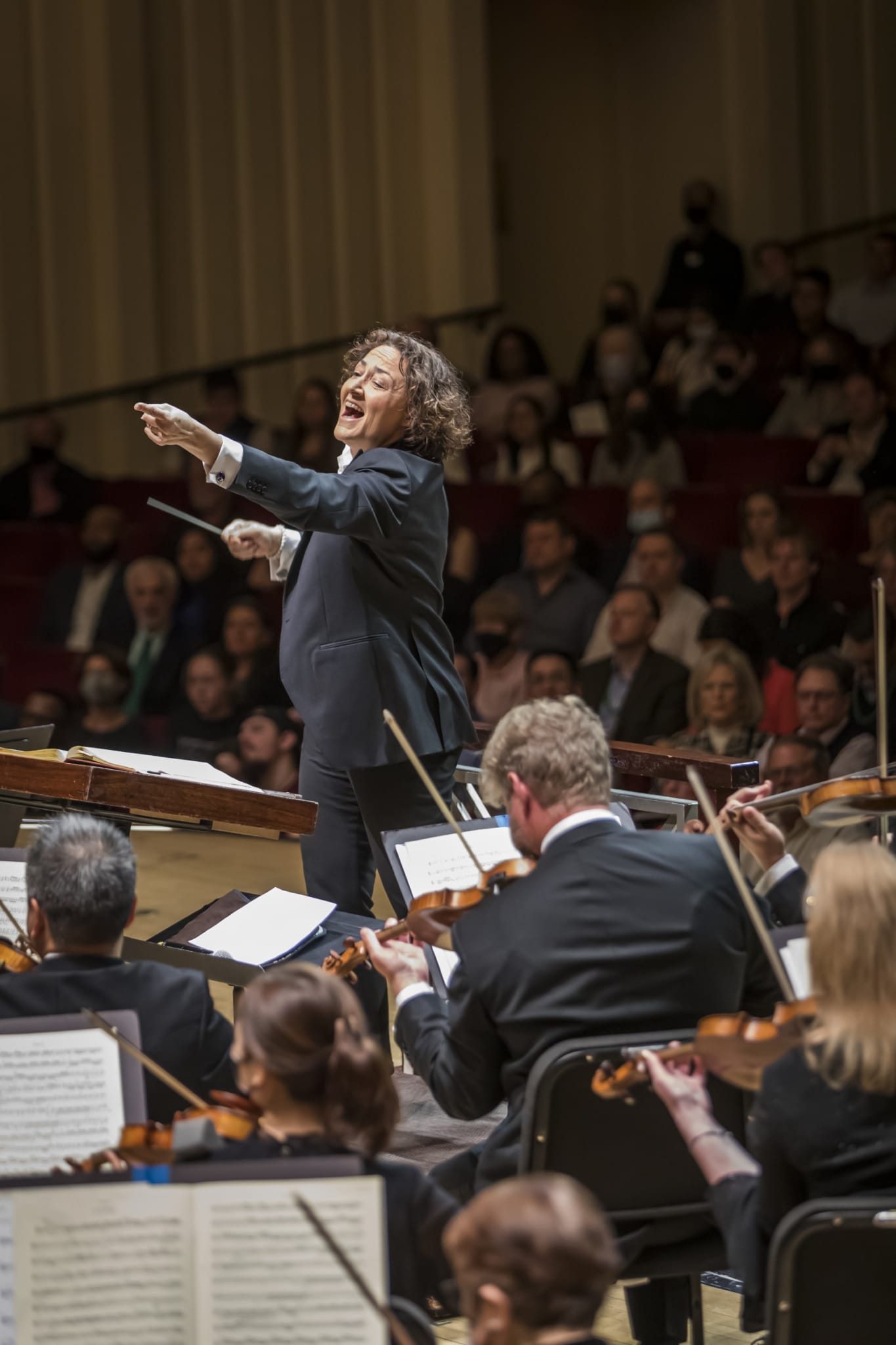 A conductor leads an orchestra in a concert hall, with musicians playing violins and other instruments in Atlanta, Georgia.