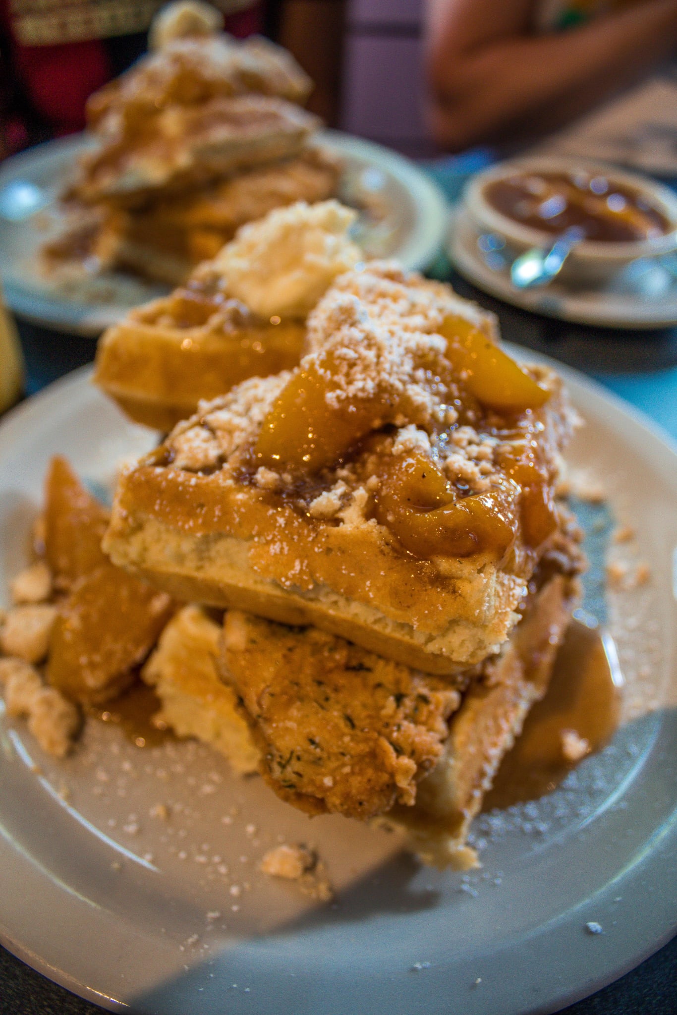 A plate of stacked waffles topped with fried chicken, peaches, and syrup in Atlanta, Georgia.