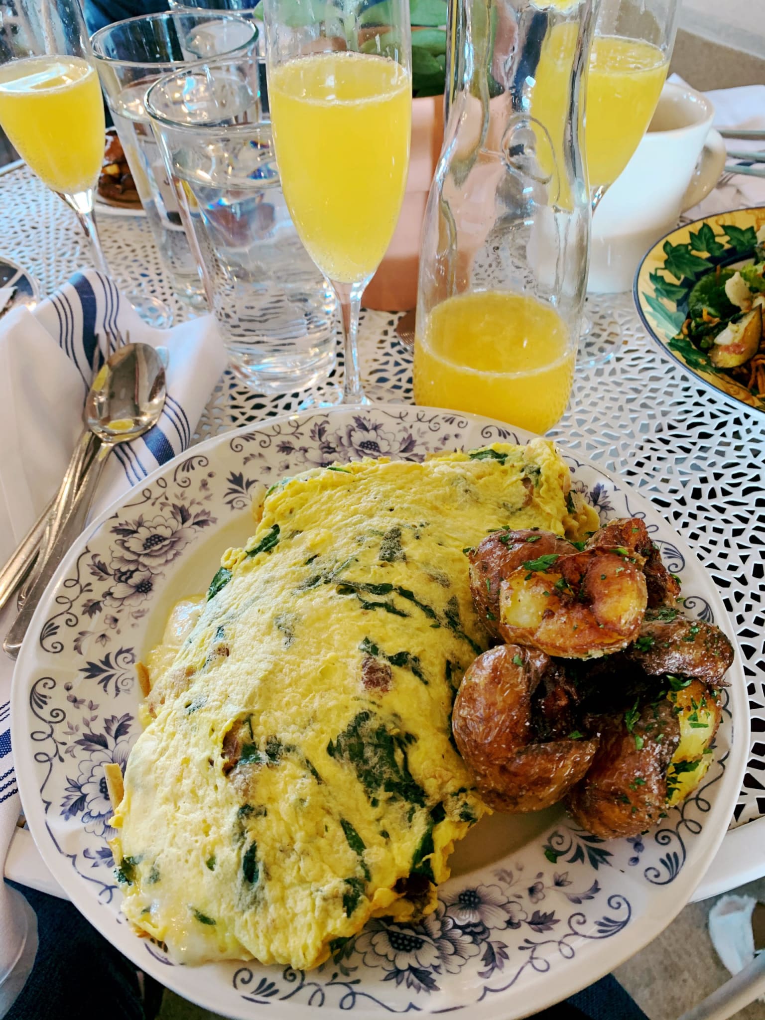 A breakfast table with a plate of spinach omelette and roasted potatoes, surrounded by glasses of orange juice in Atlanta, Georgia.