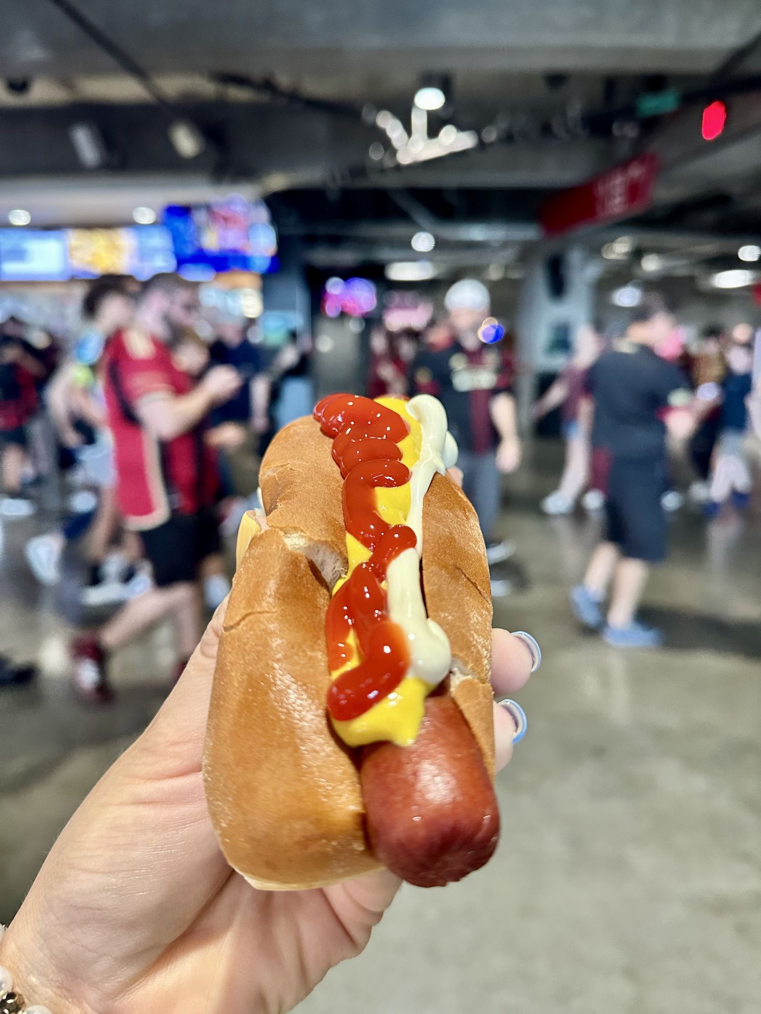 Everything You Need To Know About Mercedes-Benz Stadium in Atlanta 4 A hand holds a hot dog bun with a sausage, topped with mustard and ketchup in Atlanta, Georgia.