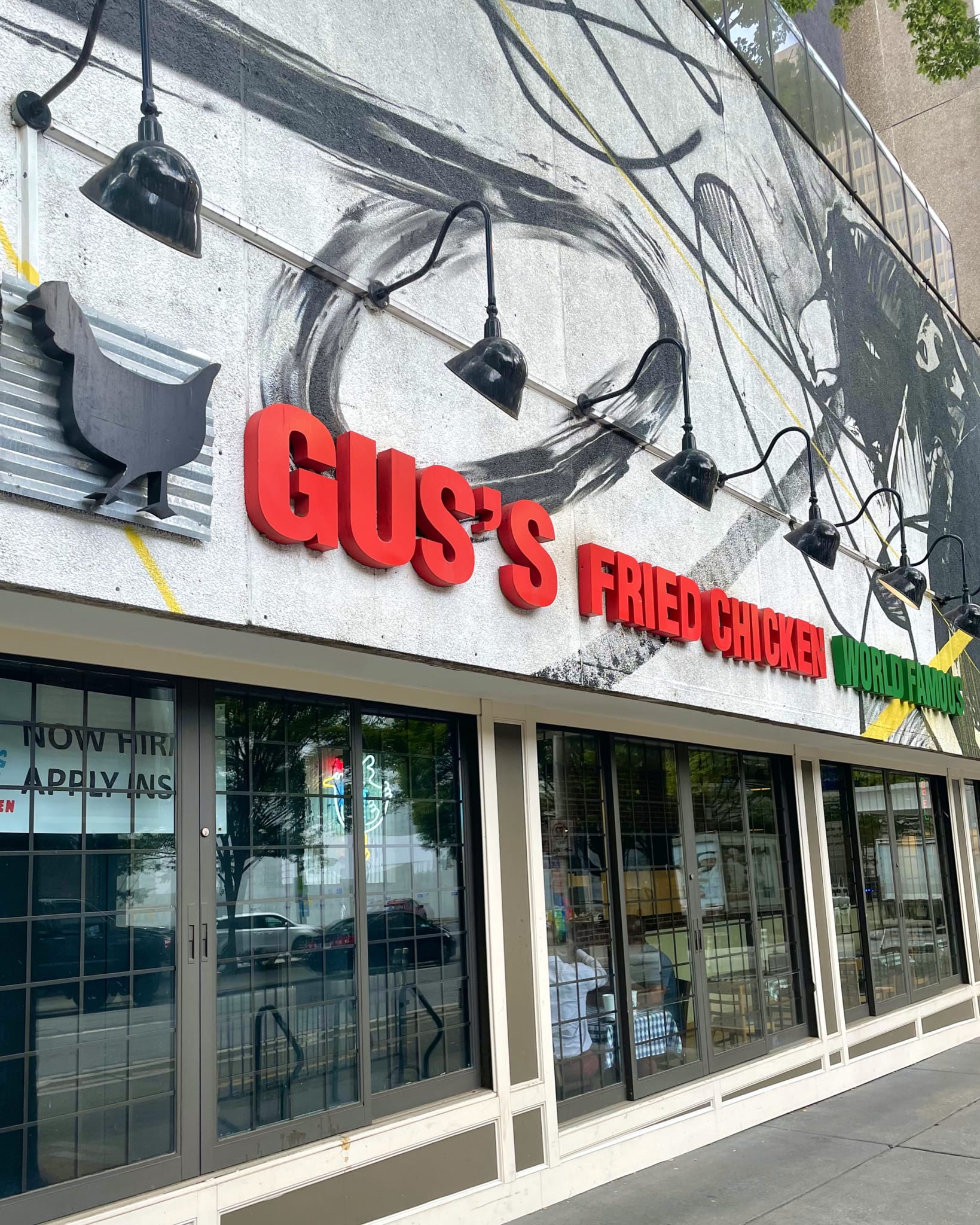 A mural of a chicken adorns the exterior of Gus's Fried Chicken, a restaurant with large windows in Atlanta, Georgia.