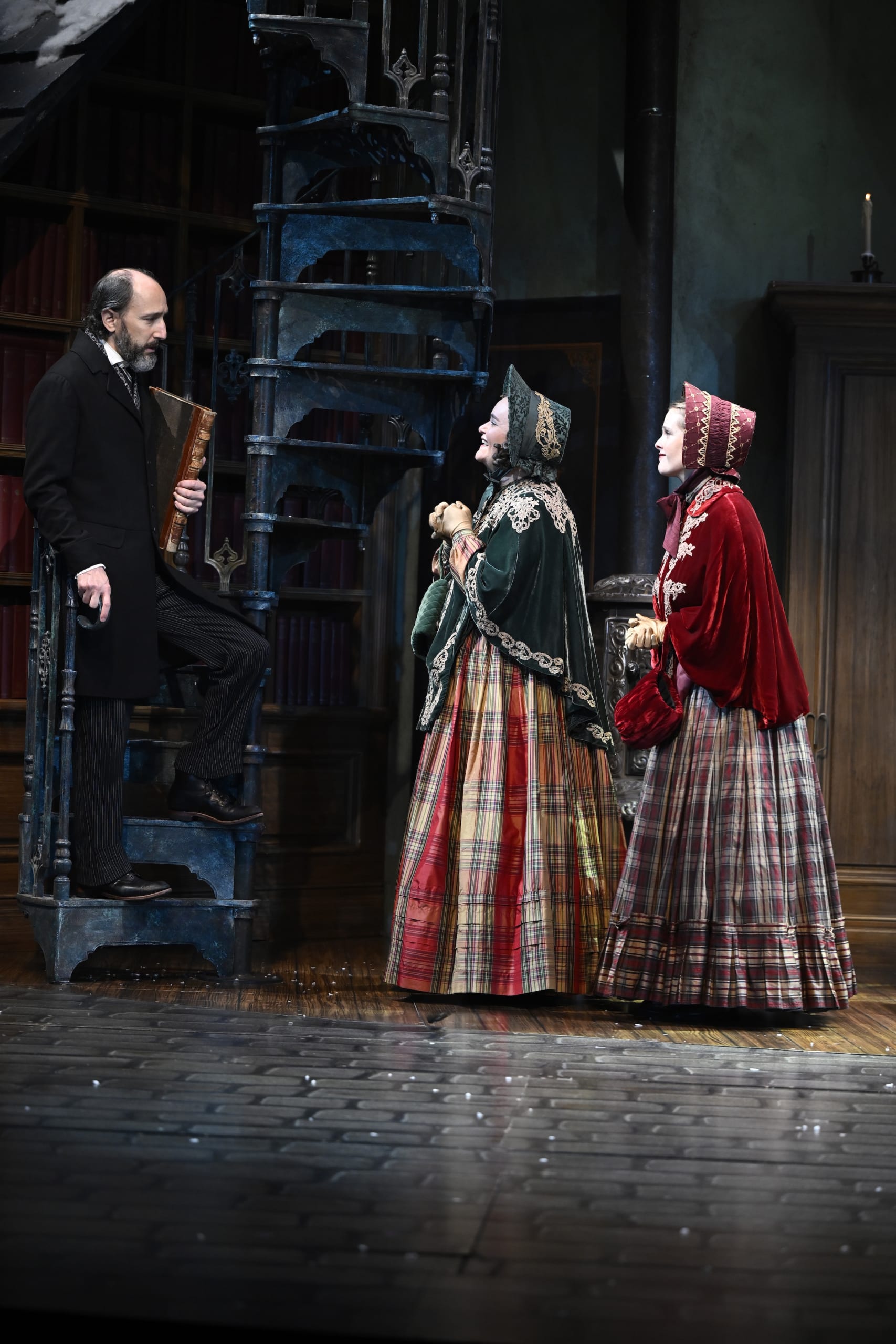Three women in Victorian-era costumes stand on a stage, facing a man in a suit on a staircase in Atlanta, Georgia.