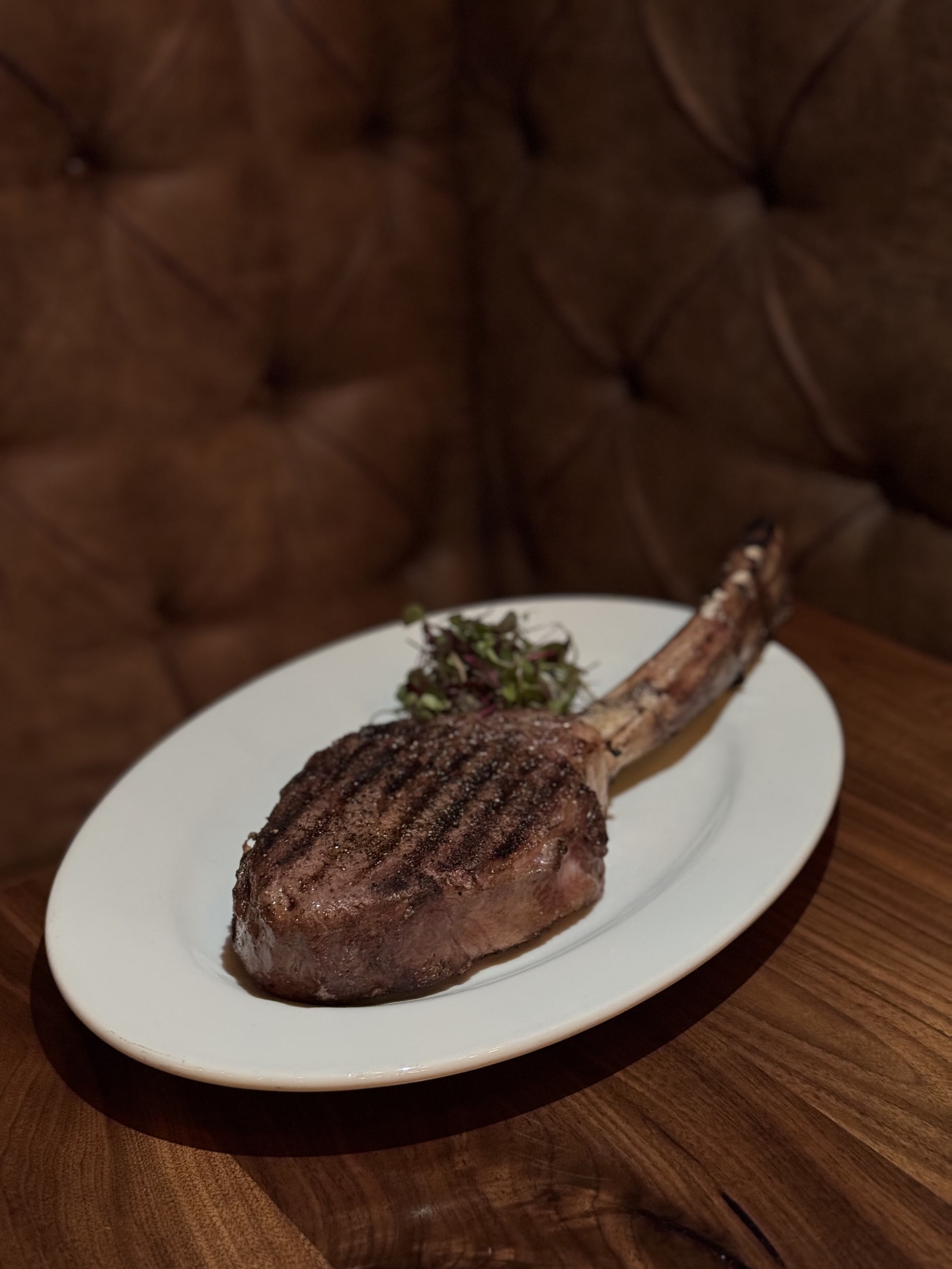 MLB ALL-STAR RESTAURANT WEEK 32 A juicy, grilled tomahawk steak with a long bone sits on a white plate in Atlanta, Georgia.